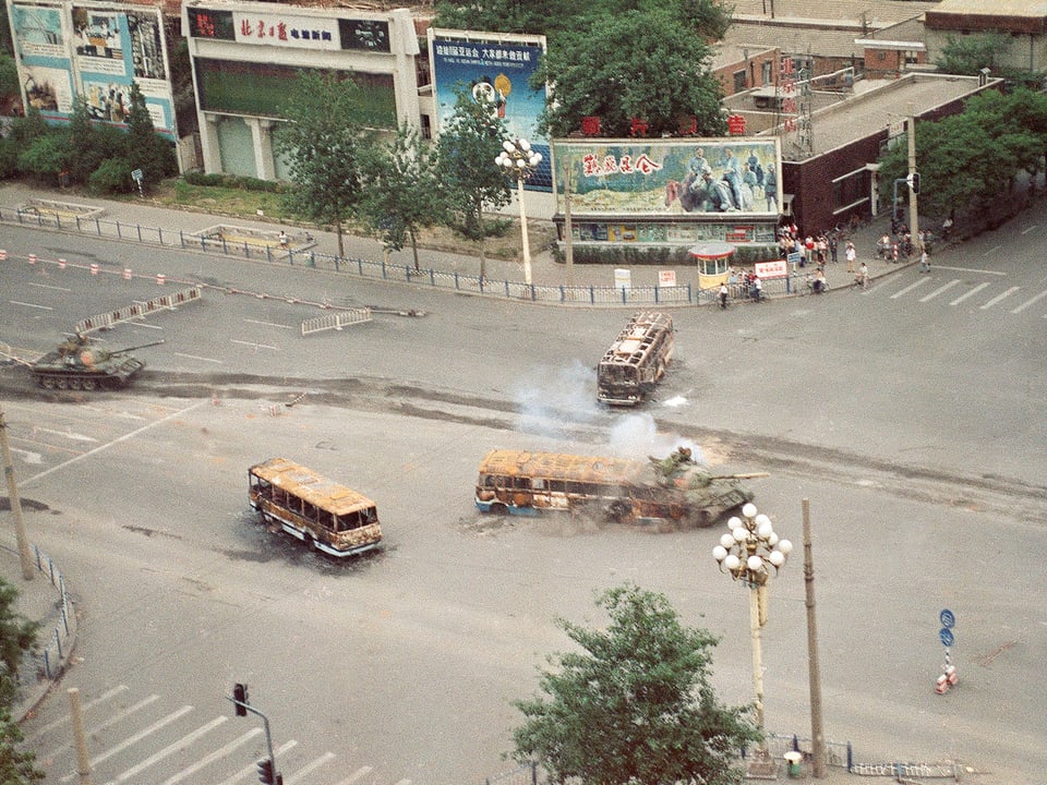 Ein Militärpanzer durchbricht eine Barrikade aus Bussen in Peking.