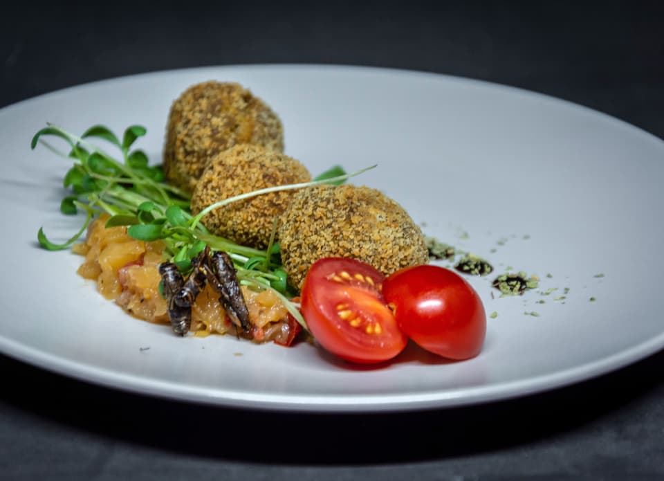 Vier Falafel-artige Kugeln mit Cherrytomaten.