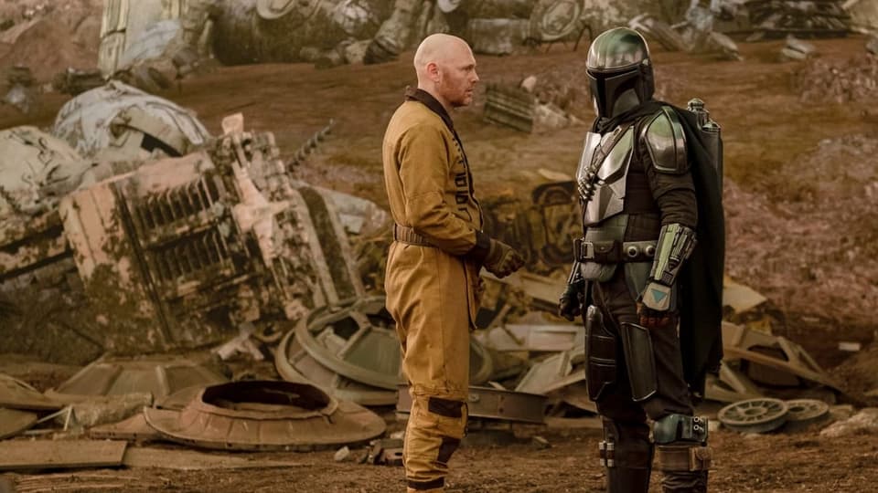 Eine Szene aus «The Mandalorian» zeigt den titelgebenden Mandalorianer zusammen mit Bill Burr.