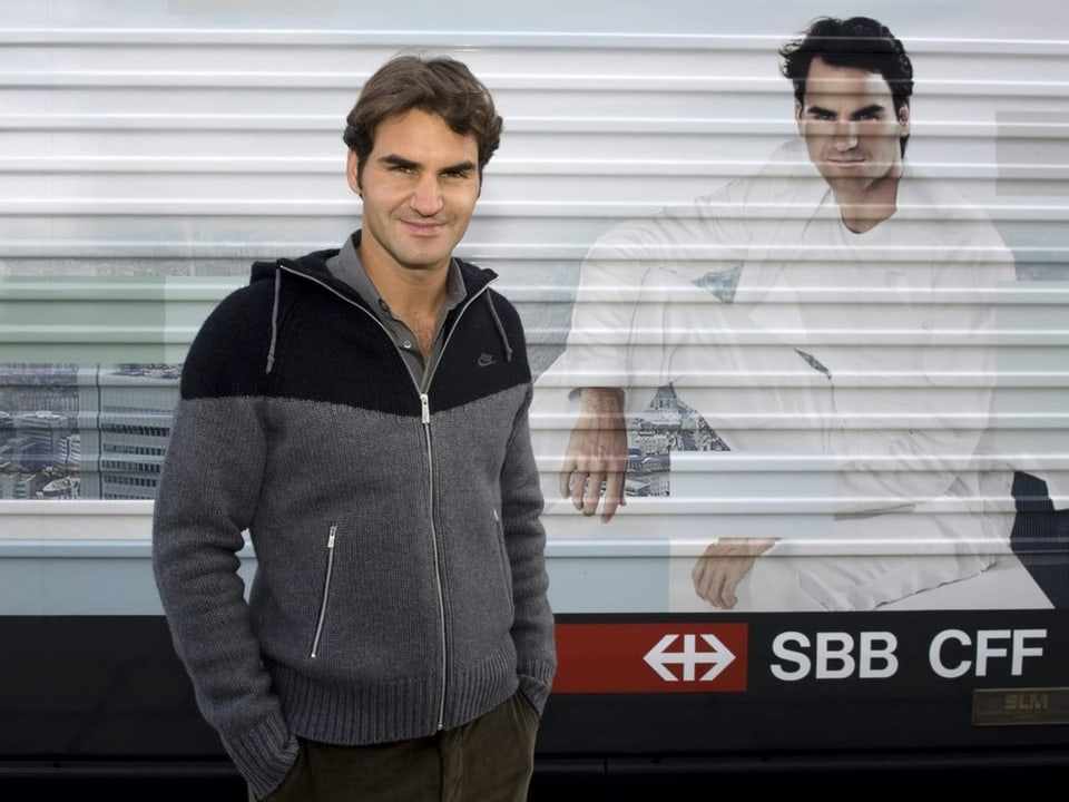 Roger Federer steht neben einer Lokomotive mit sich selber drauf.