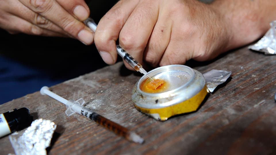 Ein Mann bereitet eine Spritze mit Heroin vor.