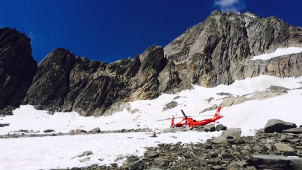 Ein Helikopter steht auf einem Schneefeld in den Bergen. 