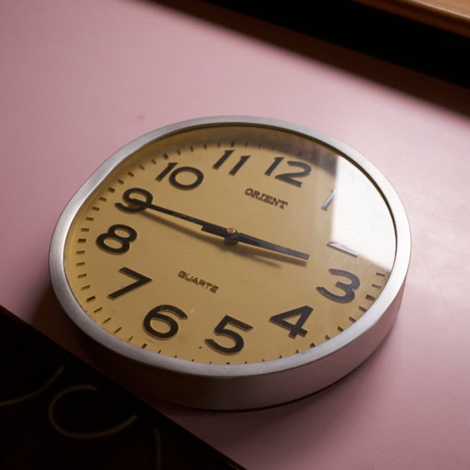 Uhr auf einem Tisch zeigt 2:45 Uhr; eine Seite ist eingedrückt.