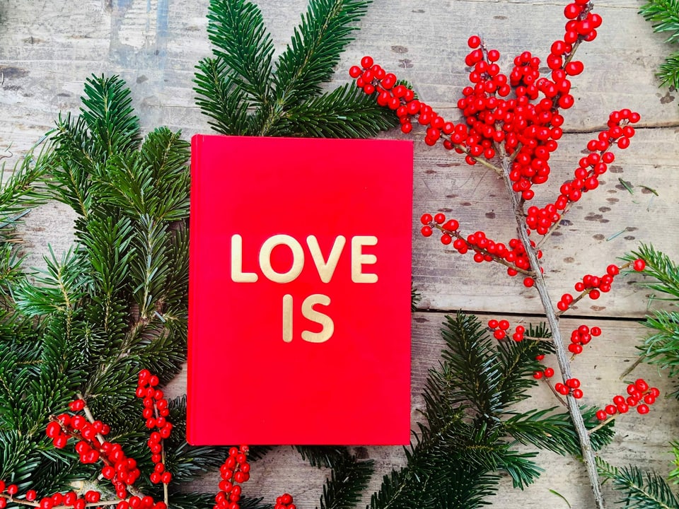 Der Almanach «Love is» von Chris & Roland Wittwer liegt auf einem Tisch mit Weihnachtsdekoration 