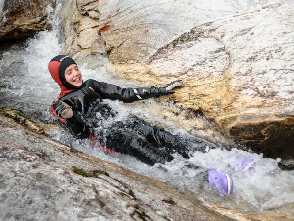 Simone Ambrosini im Neoprenanzug liegt gerade im Wasser, das ihn zwischen zwei Felsen hinunter schleust.