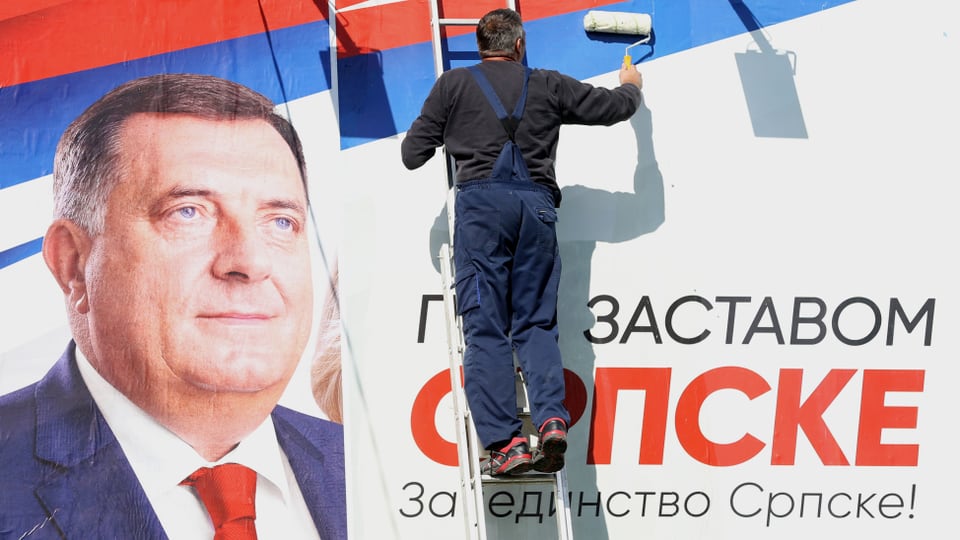 Mann befestigt Wahlplakat von Milorad Dodik