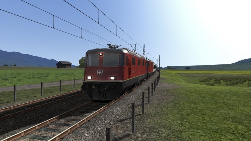 Ein roter Zug mit Schweizerkreuz allein auf weiter Flur. 