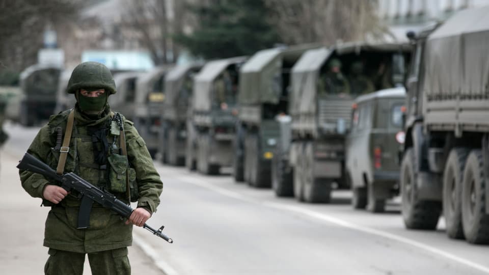 Soldat beobachtet einen Konvio von Militärfahrzeugen.