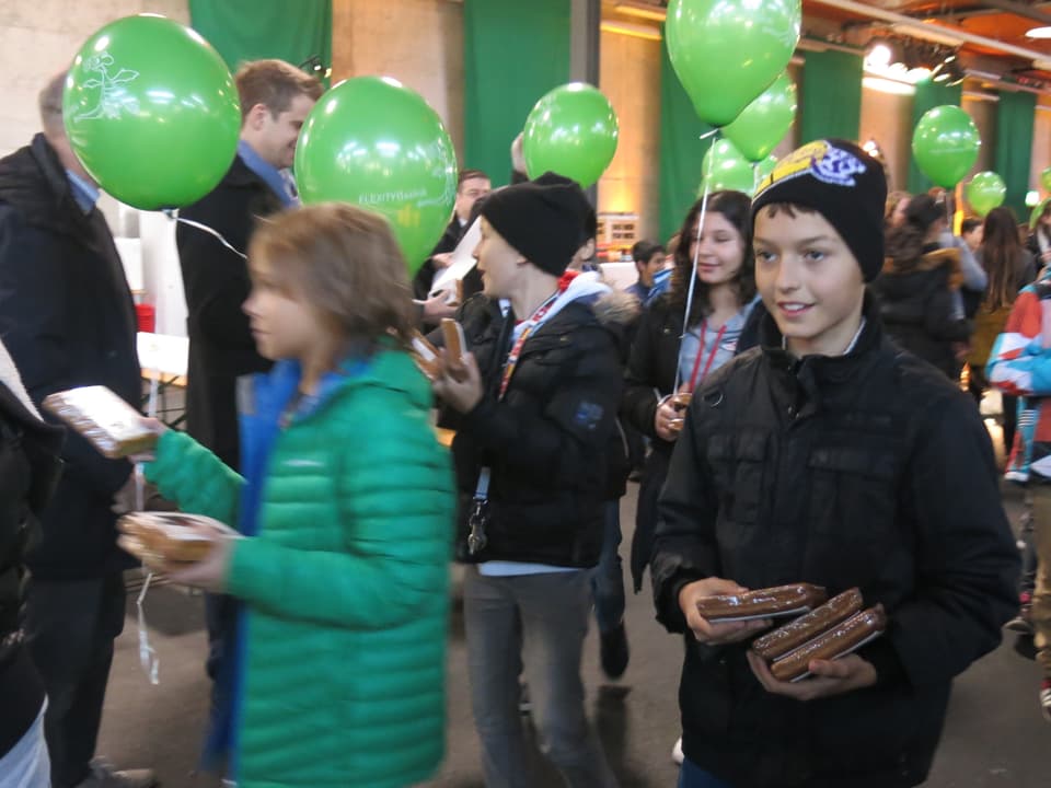 Schulkinder mit grünen BVB-Ballonen verteilen Lebkuchen.