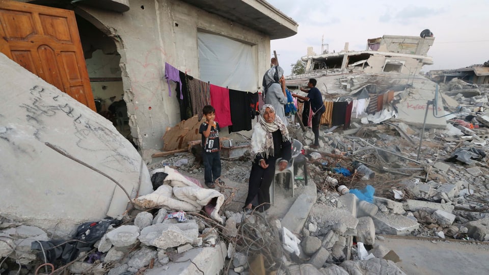 Frau und Kinder, umgeben von Trümmern ihres Hauses.