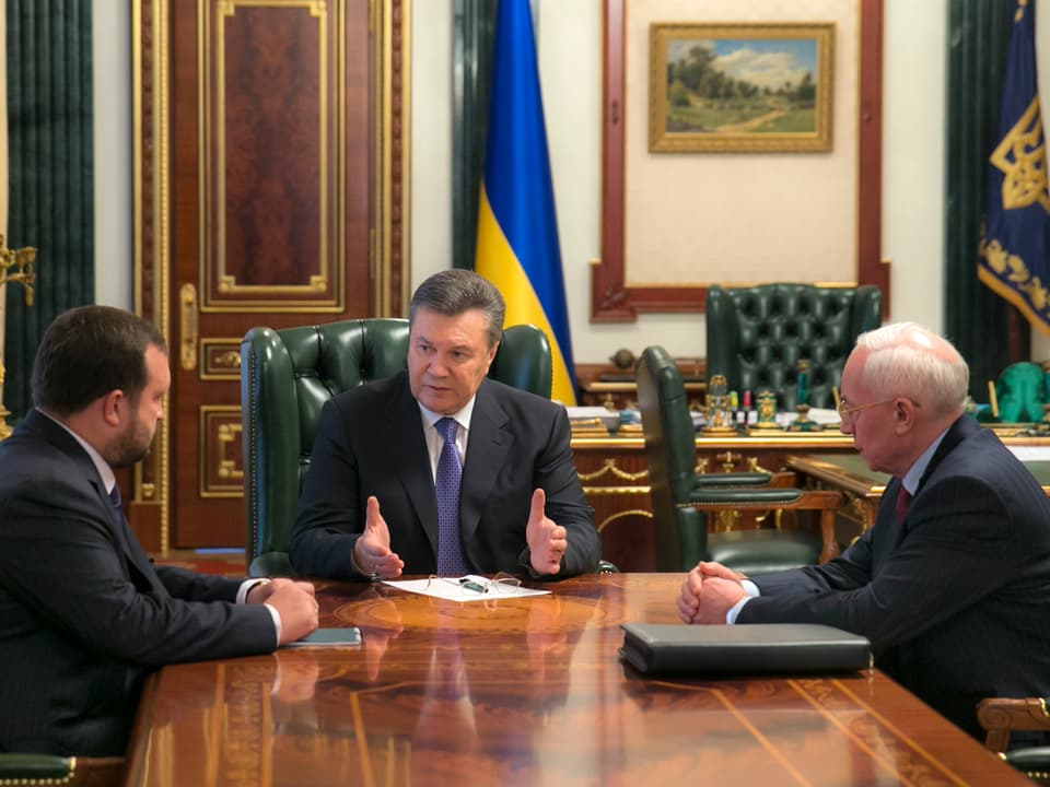 Janukowitsch und die zwei Minister sitzen an einem Tisch.