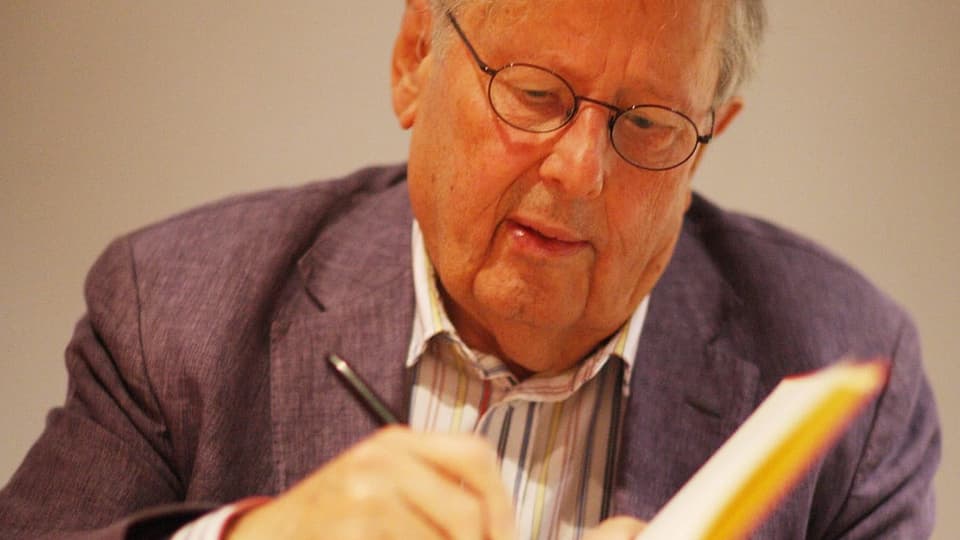 Foto älterer Mann mit Anzug unterschreibt in Buch