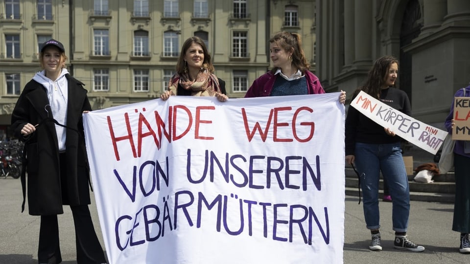 Juso-Präsidentin Ronja Jansen und weitere Teilnehmerinnen einer Kundgebung halten Plakate.