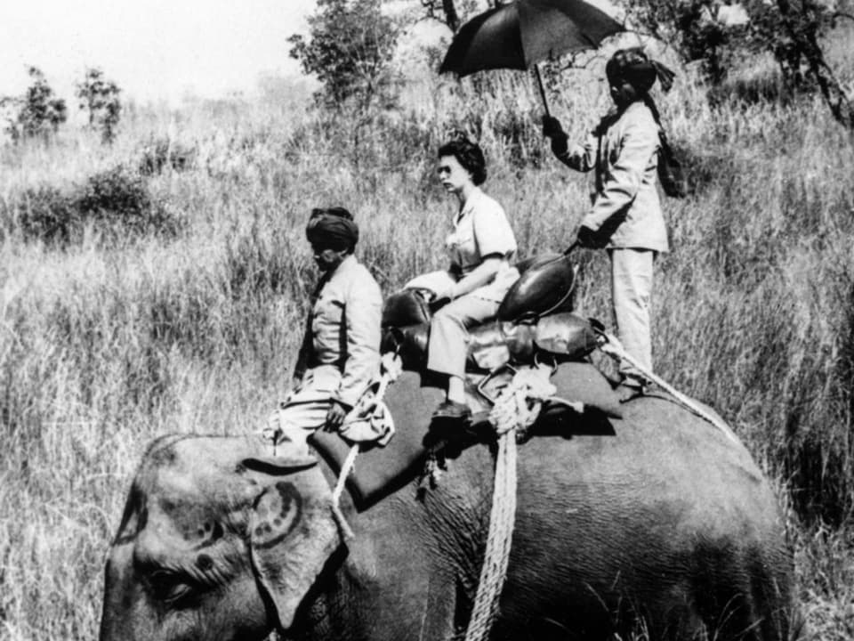 Schwarzweissfoto: Frau mit zwei uniformierten Männern auf einem Elefanten.