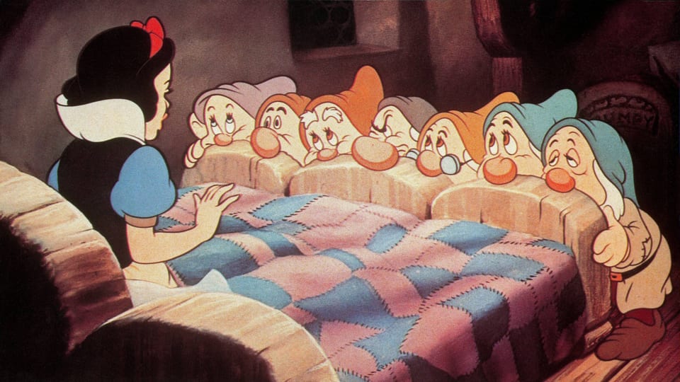 Zeichentrickbild: Die sieben Zwerge stehen am Bettende von Schneewittchen und schmachten sie an.