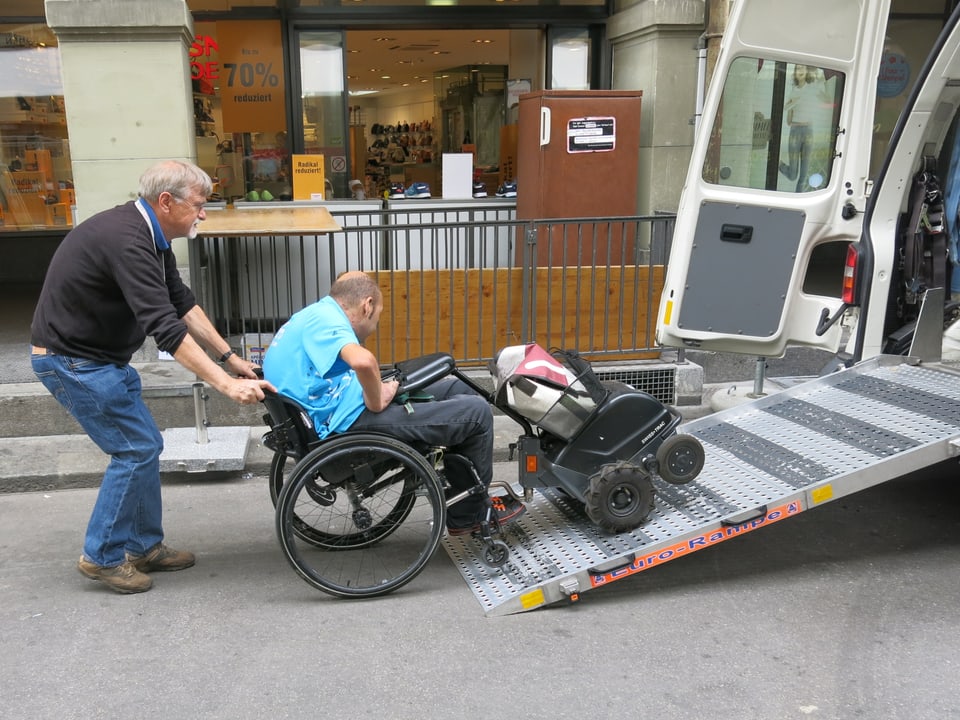 Ein Mann hilft einem Rollstuhlfahrer.