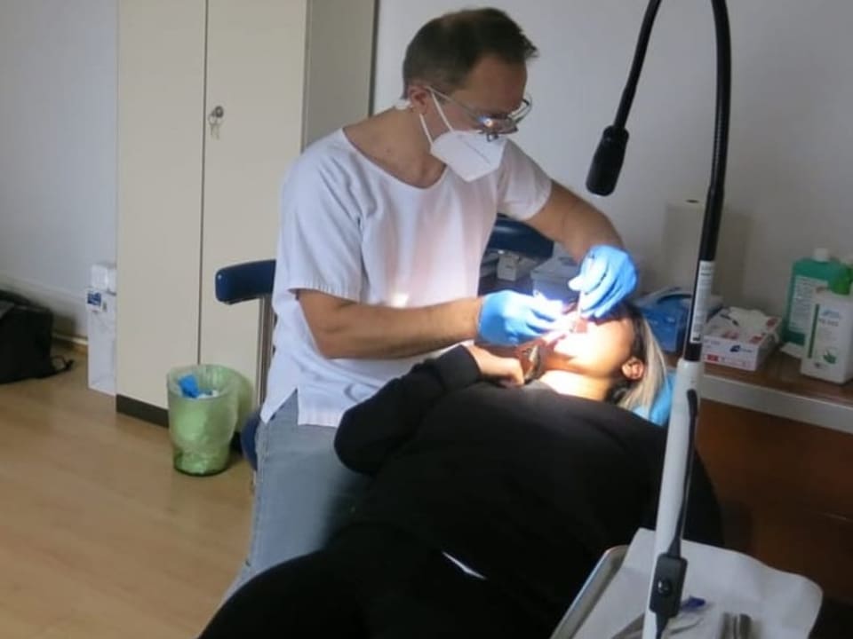 Zahnarzt behandelt eine Frau in einem umfunktionierten Büro.
