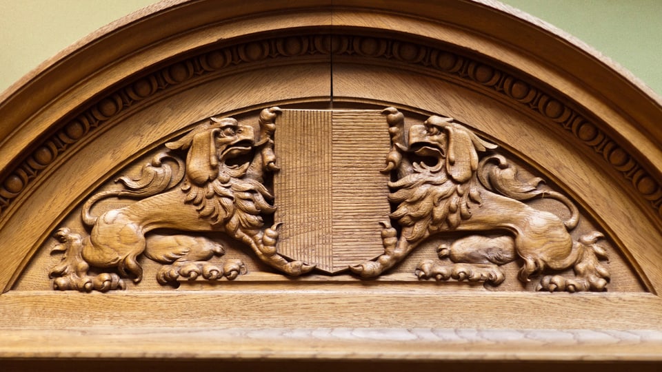 Emblem aus Holz im Nationalratssaal mit dem Tessiner Wappen.