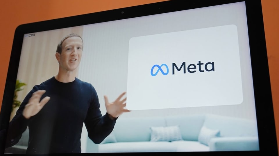 Mark Zuckerberg auf Bildschirm, daneben Meta-Logo