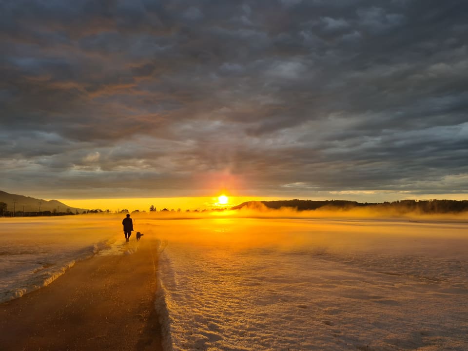 Gelber bis oranger Sonnenuntergang über weisser Landschaft mit Hagel.