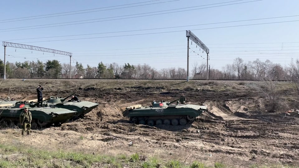 Mehrere russische Panzer stehen hintereinander neben Bahngeleisen 