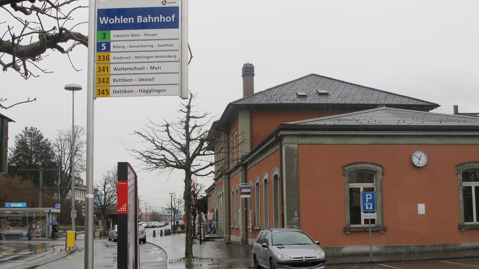 Bahnhofsgebäude in Wohlen, im Vordergrund Bus-Schild