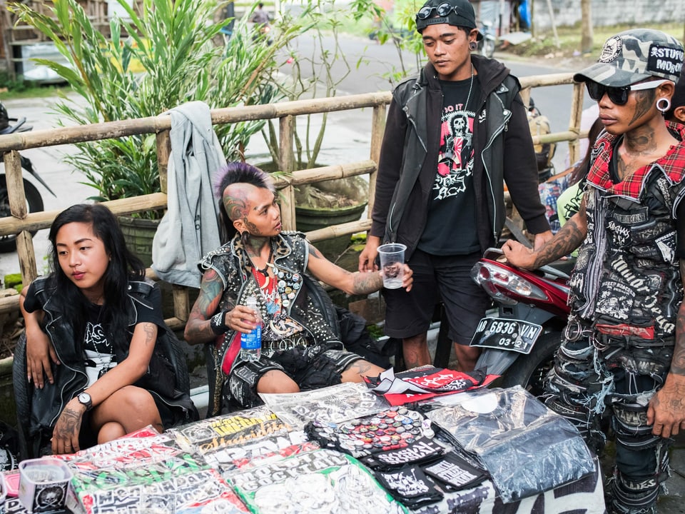 Eine Gruppe Punks sitzt an einem Stand mit selbstgemachten Artikeln wie T-Shirts und Pins.