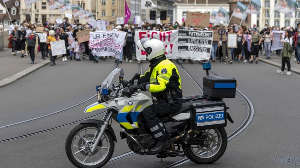 Motorfahrzeug der Polizei. Im Hintergrund Demonstrationsteilnehmerinnen. 