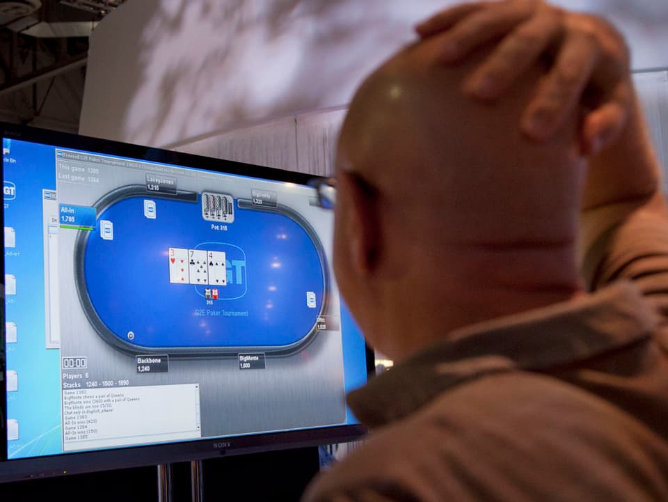 Ein Mann steht erregt vor einem Monitor, der ein Pokerspiel zeigt.