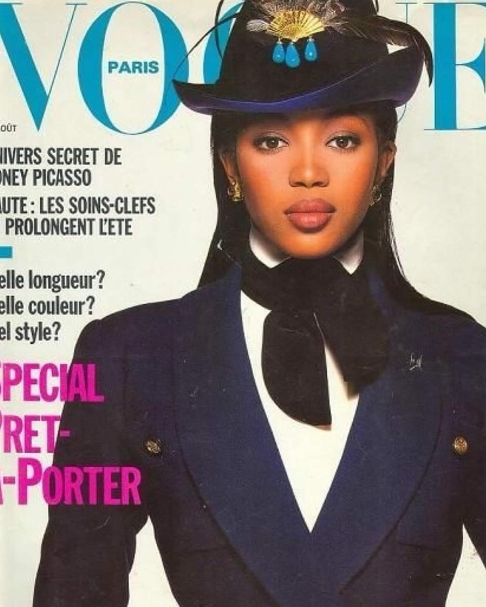 Vogue-Cover mit Naomi Campbell. Sie trägt eine Art dunkelblaue Uniform mit Jägerhut und schaut direkt in die Kamera.