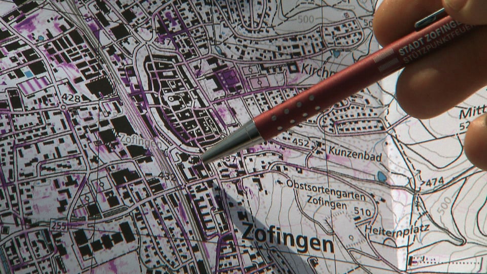 Karte mit lila Stellen, zu sehen ist die Altstadt von Zofingen. Daneben zeigt jemand mit einem Kugelschreiber auf die Karte.