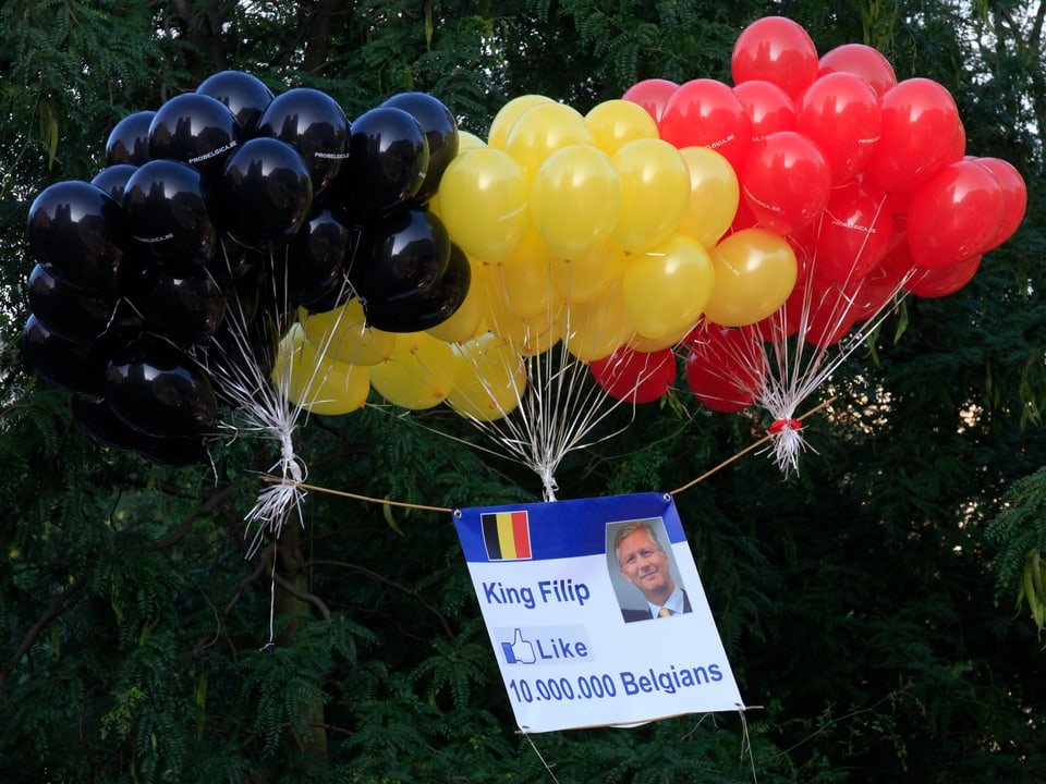 Ballons in den Farben der belgischen Flagge. Angehängt ein Plakat mit dem Foto von Philippe.