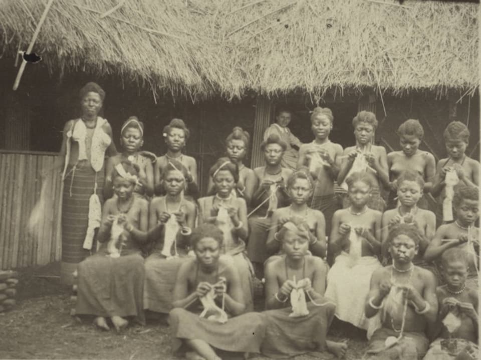 Schwarz-Weiss-Foto: Eine Gruppe von jungen afrikanischen Mädchen strickt. 