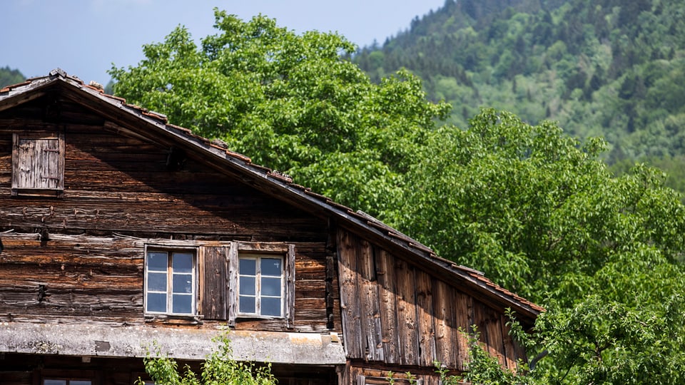 Kleine Fenster, dunkles Holz: Das rund 700-jährige Holzhaus an der Lauigasse in Steinen mit Bäumen im Hintergrund.