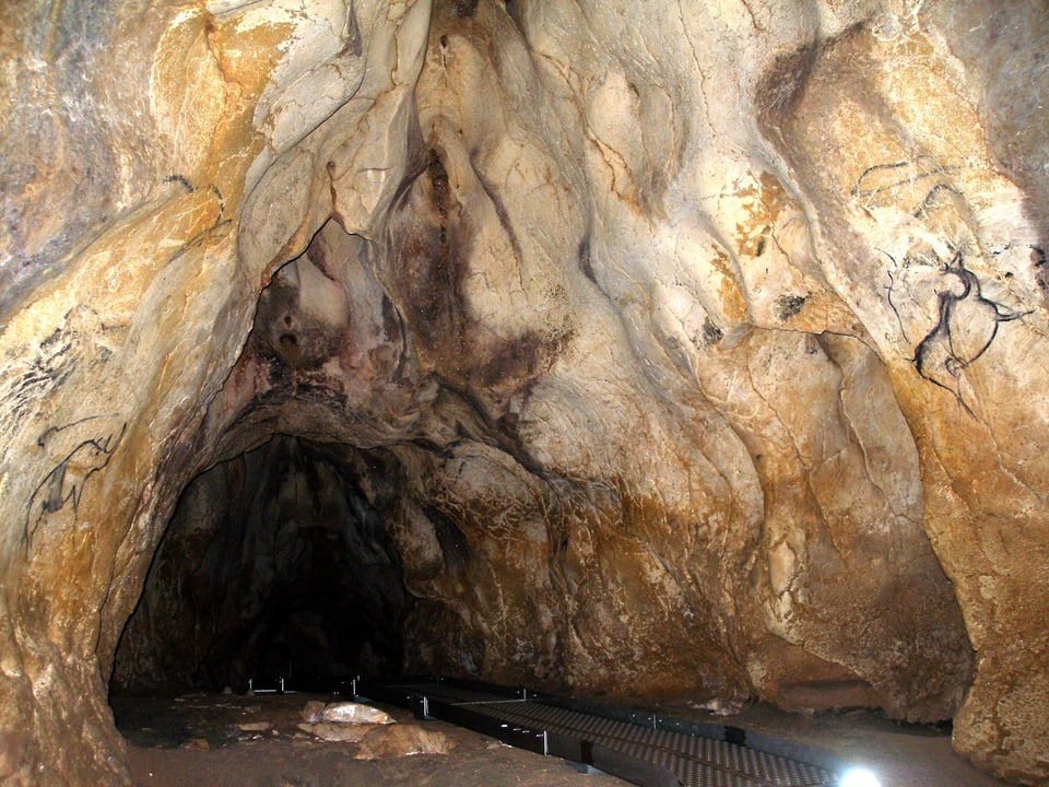 Dunkler Höhleneingang, umrahmt von hellem Gewölbe.