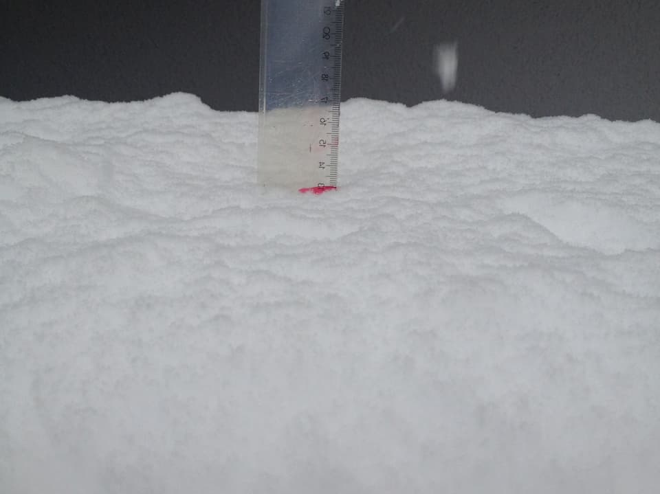 Ein Lineal steckt bis zur 13 cm Marke im Schnee