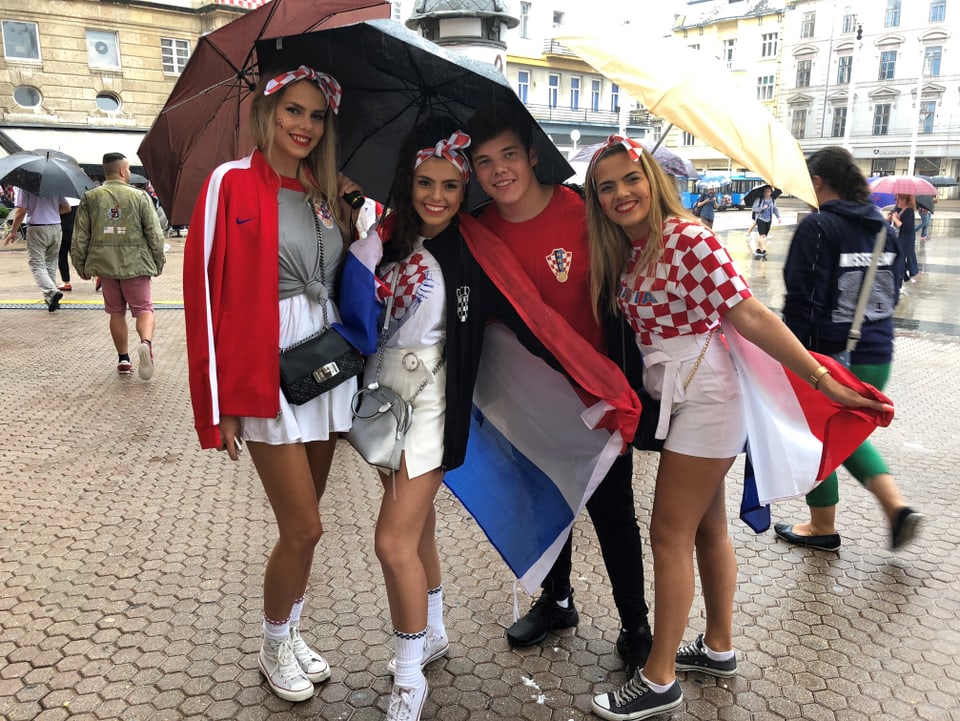 Weibliche Fans unter Regenschirmen.