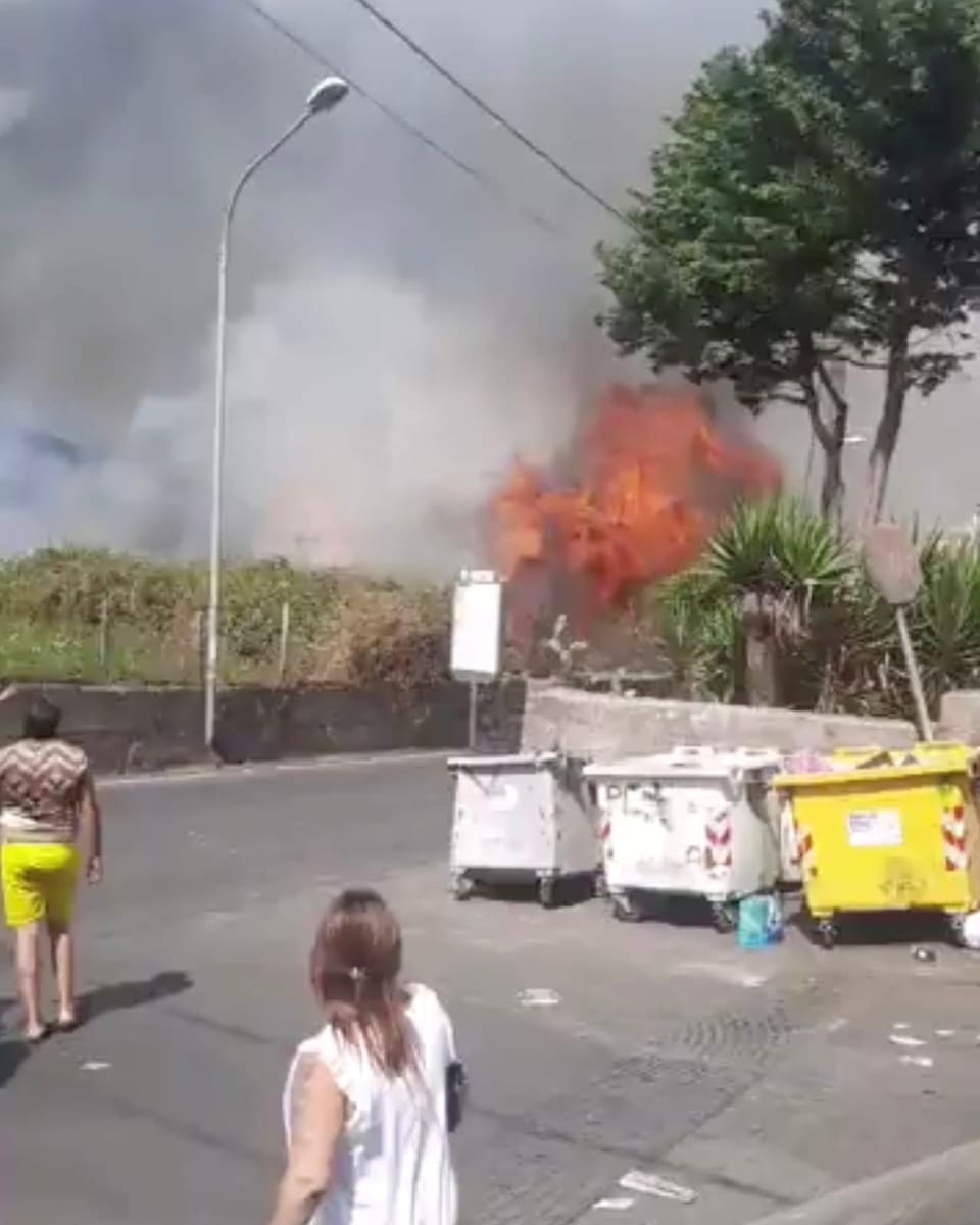 Passanten stehen auf der Strasse und beobachten Meterhohe Flammen im Hintergrund.