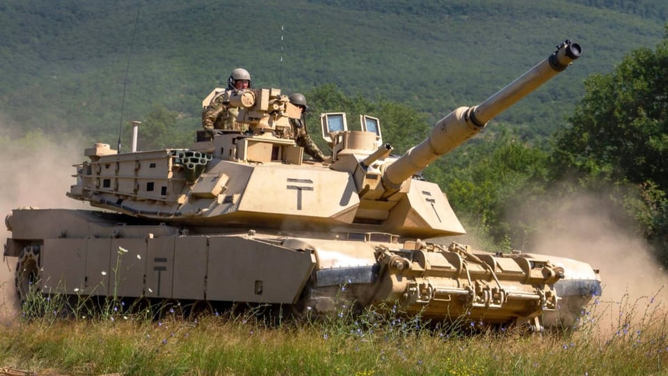 Der M1 Abrams wird von einem Soldaten auf einem Feld gefahren. 
