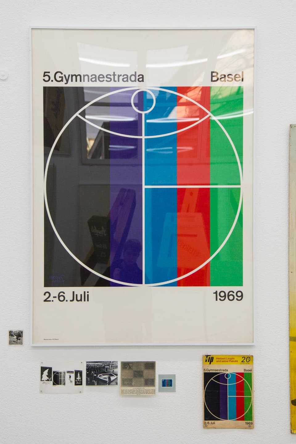 Ein Plakat zeigt ein Strichmännchen in einem Kreis, dahinter sind verschiedene Farbstreifen zu erkennen.