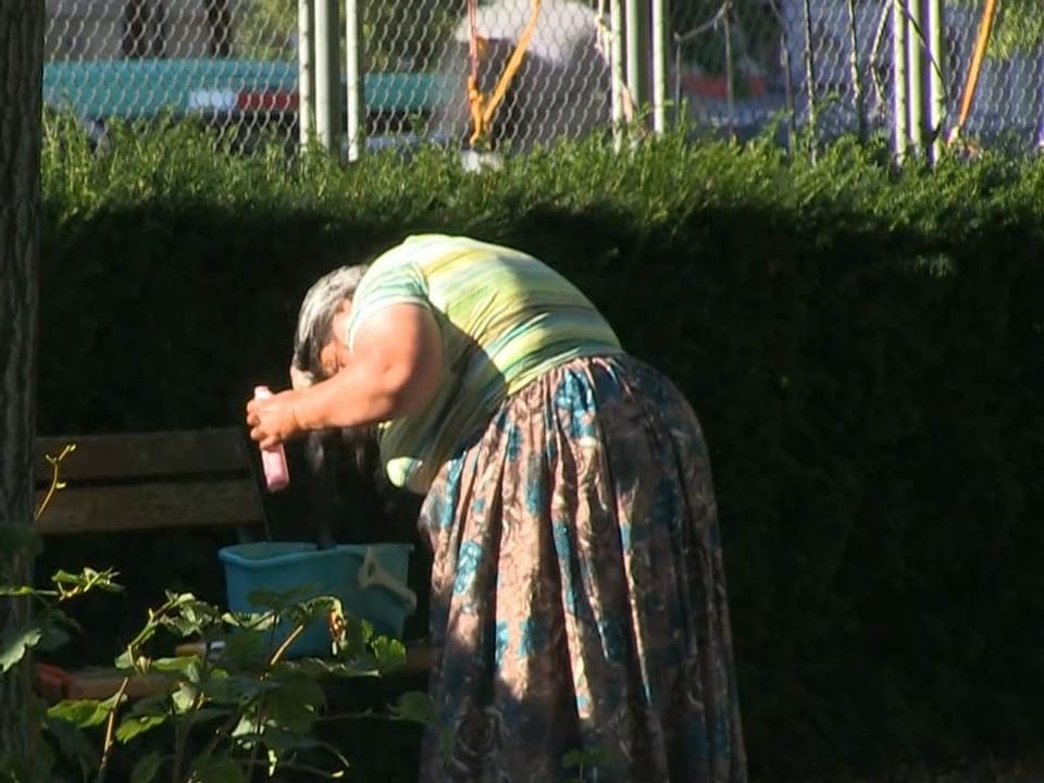 Eine Frau wäscht ihre Haare in einem Park.