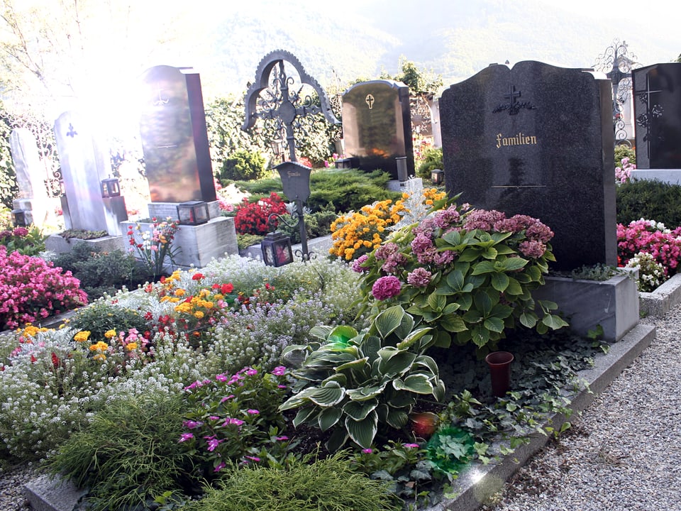 Ein üppig bepflanztes Familiengrab mit Grabstein.