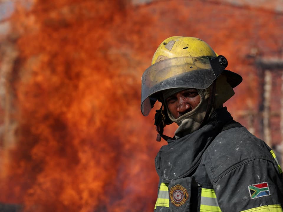 Ein Feuerwehrmann: in Hintergrund ein Brand.