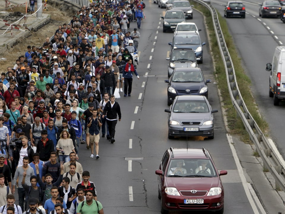 Flüchtlinge laufen eine Strasse entlang Richtung Österreich 