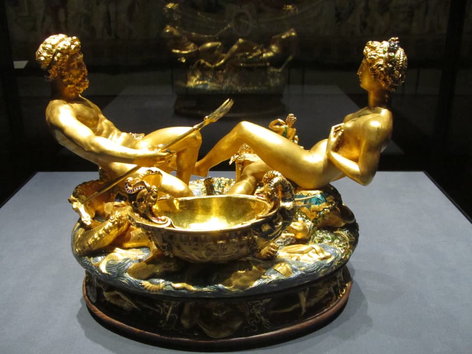 Skulptur aus Gold: Zwei halb liegend-halb sitzende Figuren, davor eine Schale. 