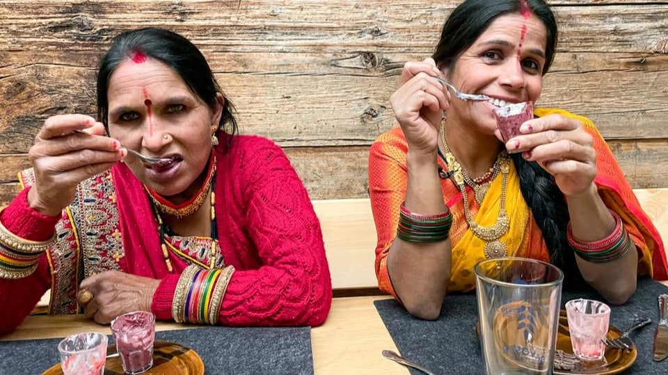 Gayatri und Bhagwati tragen einen Sari und essen Dessert.