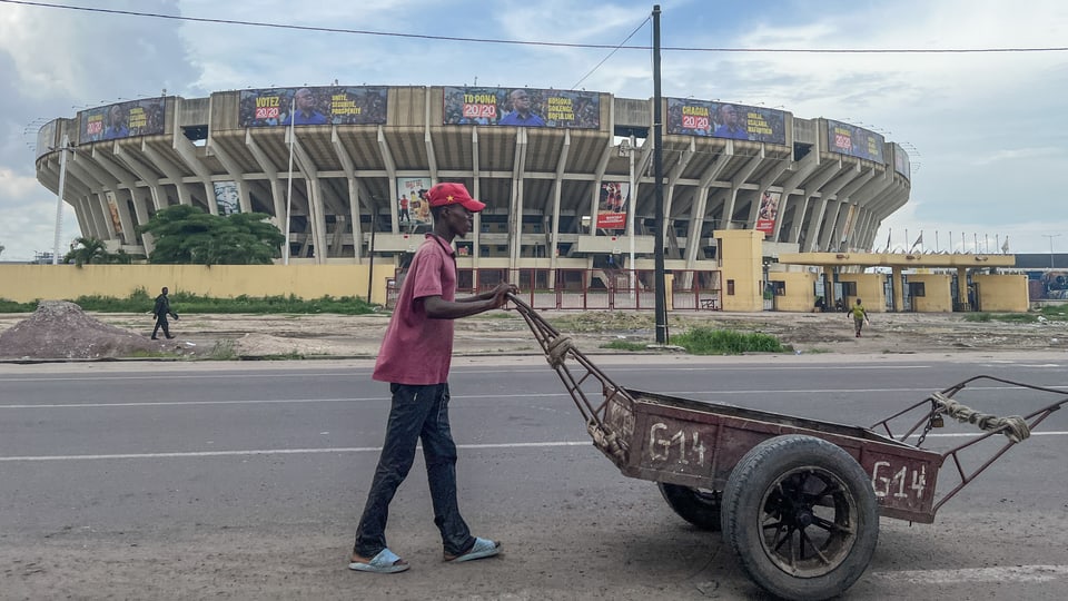 Mann schiebt einen Karren vor dem Fussballstadion