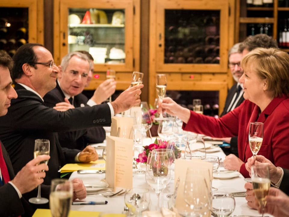 François Hollande (l) und Angela Merkel (r) sich gegenseitig zuprostend