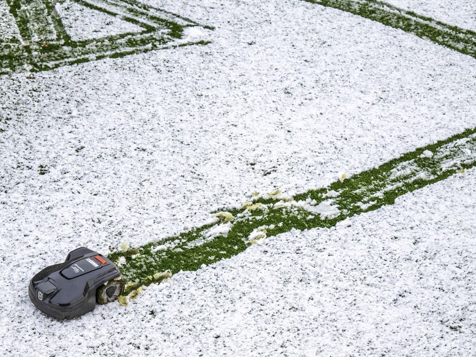 Auto versinkt im Schnee auf einem Parkplatz mit Reifenspuren.