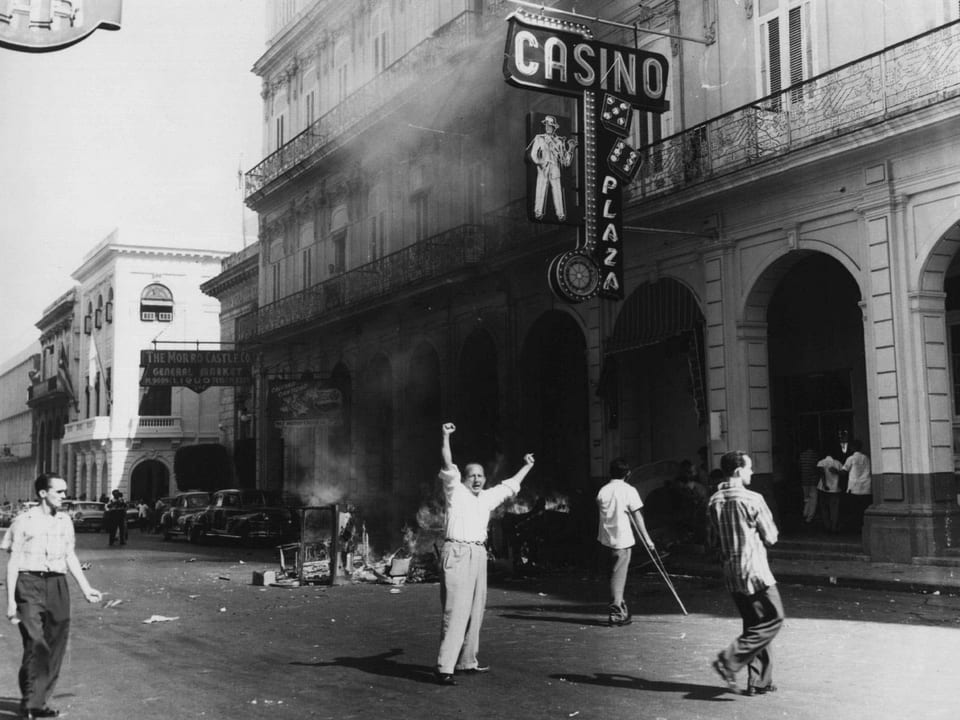 Ein brennendes Casino in Havanna, 1959. Davor jubeln Menschen.